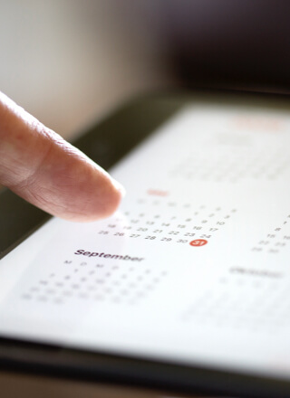 Ein Finger zeigt auf einen digitalen Kalender auf einem Tablet